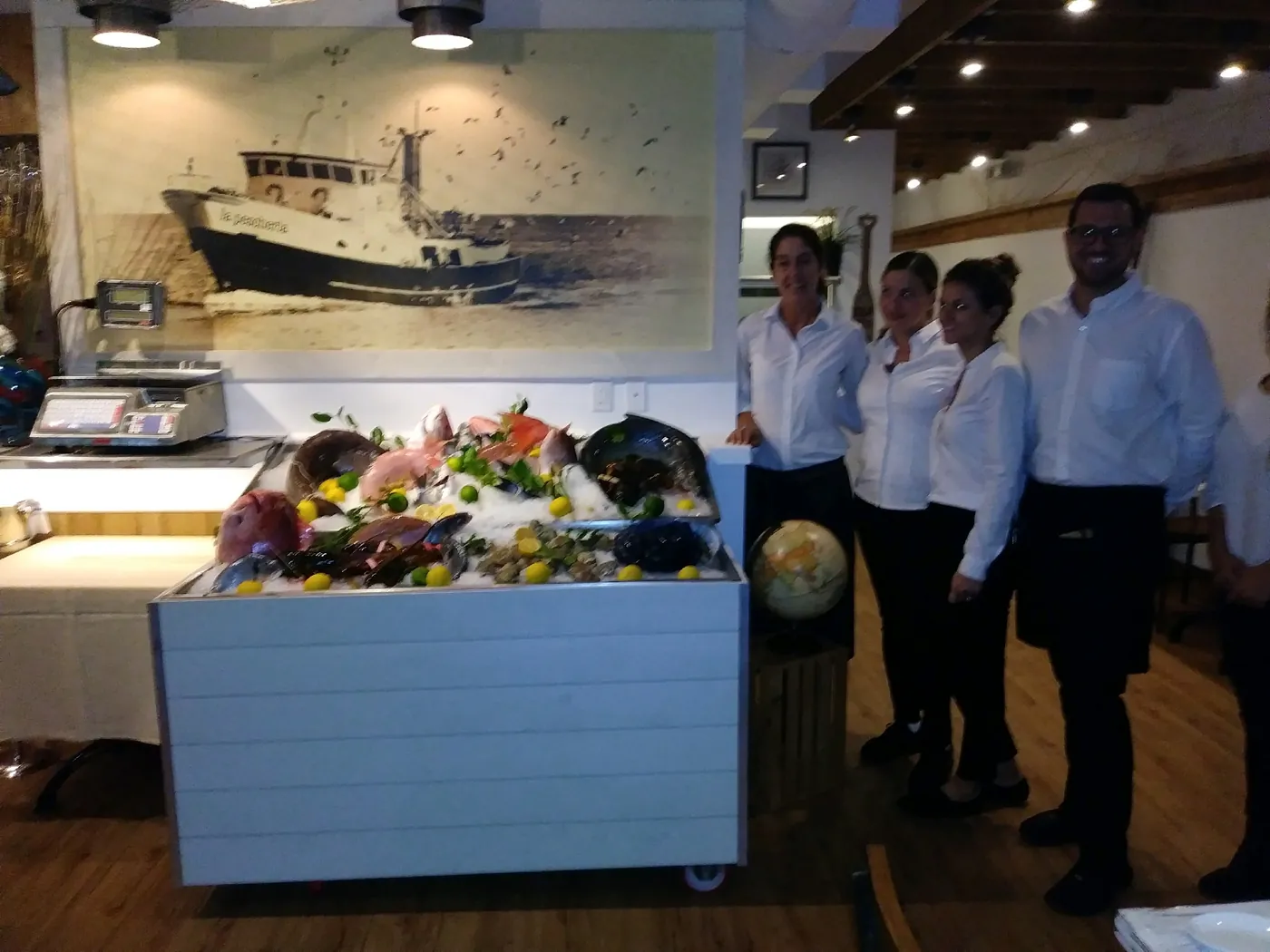 The La Pescheria team beside the fish display and fishing-boat mural